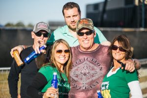 Runaway Country Music Fest, three men and two women in green hug & smile with drinks